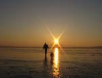 Ein Mann geht mit seinem Hund bei Sonnenaufgang über den See